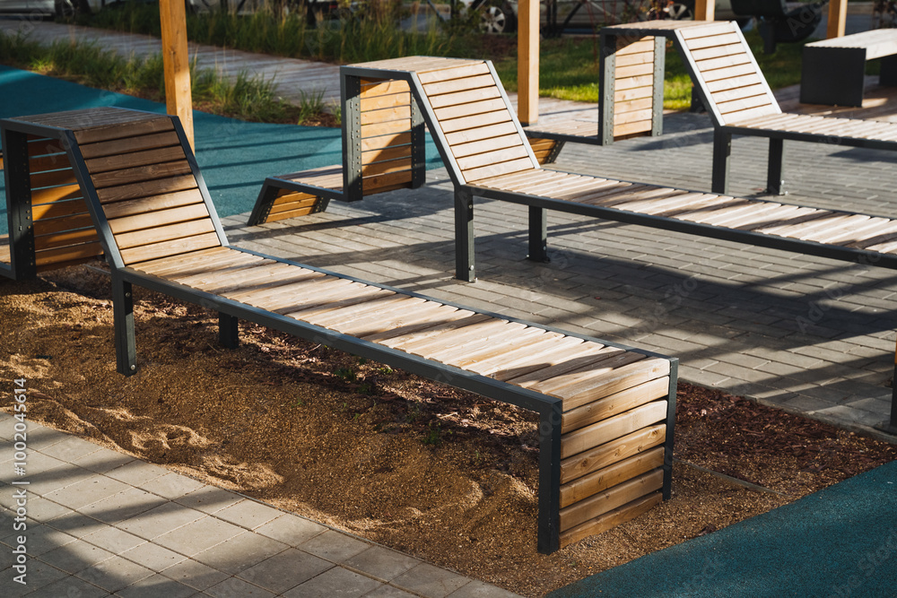 Obraz premium A row of wooden lounge chairs are sitting in the sand near a pool