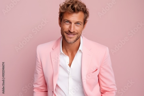 Portrait of a handsome young man in a pink suit on a pink background