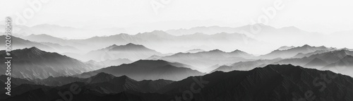 A serene black and white landscape showcasing misty mountain ranges under a soft sky, evoking tranquility and depth.