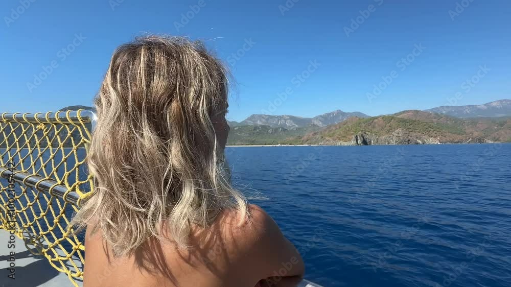 A blonde woman is enjoying the view on the yacht A blonde woman is enjoying the view on the yacht