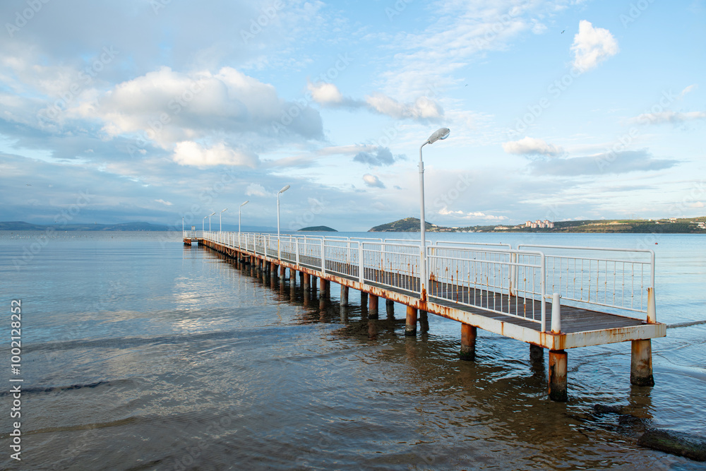 Naklejka premium Wooden walking track built on the sea. Wooden bridge by the sea. Walking track with wooden floor and iron railings built in the sea. Quay walking area. Sea of ​​Erdek.