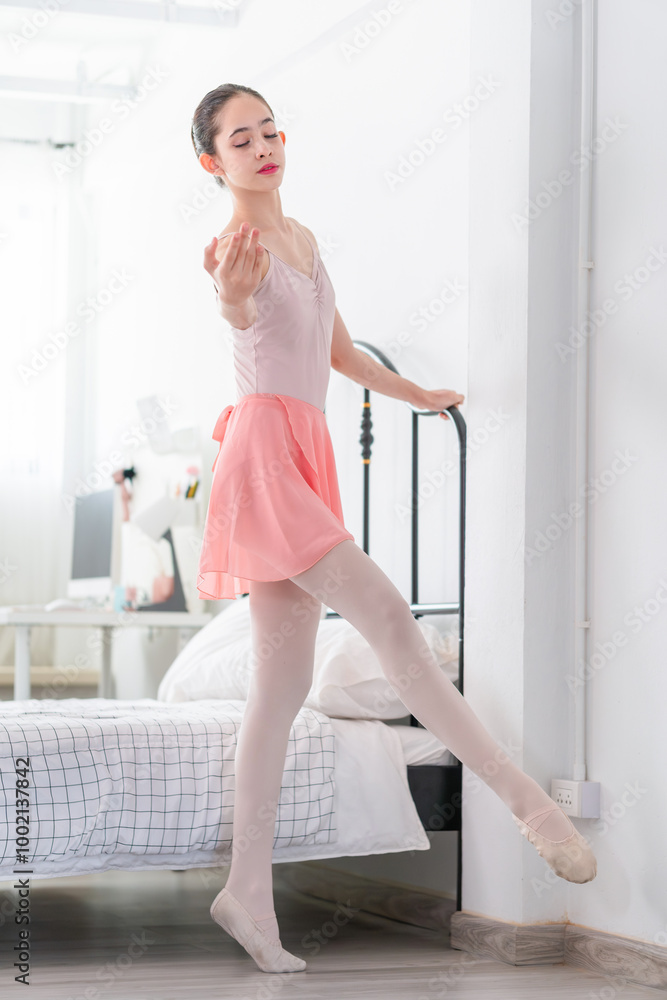 A young girl practices her stretching routine in bedroom before practicing ballet, Young dancer warming up in ballet studio A young girl practices her stretching routine in bedroom before practicing ballet, Young dancer warming up in ballet studio