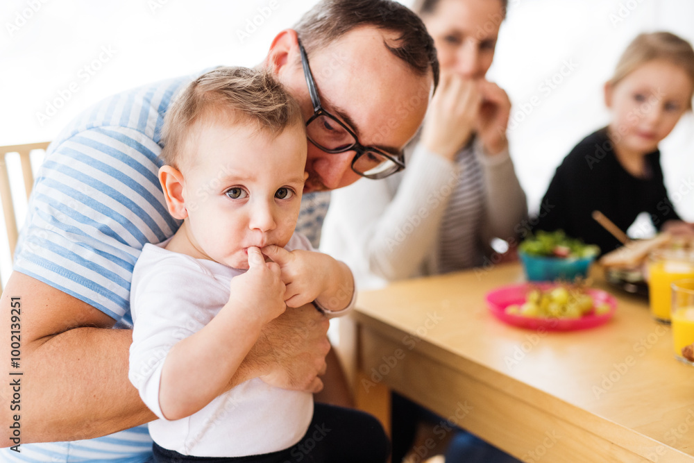 Parents with two children eating a tasty, healthy breakfast in the kitchen. Happy family moment. Parents with two children eating a tasty, healthy breakfast in the kitchen. Happy family moment.