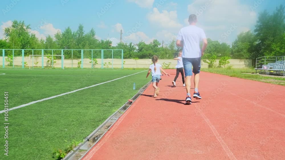 Dad and his child girl in sportswear are smiling and running at the sports ground. Father spends time with daughter. Summer sunny day. Slow motion Dad and his child girl in sportswear are smiling and running at the sports ground. Father spends time with daughter. Summer sunny day. Slow motion