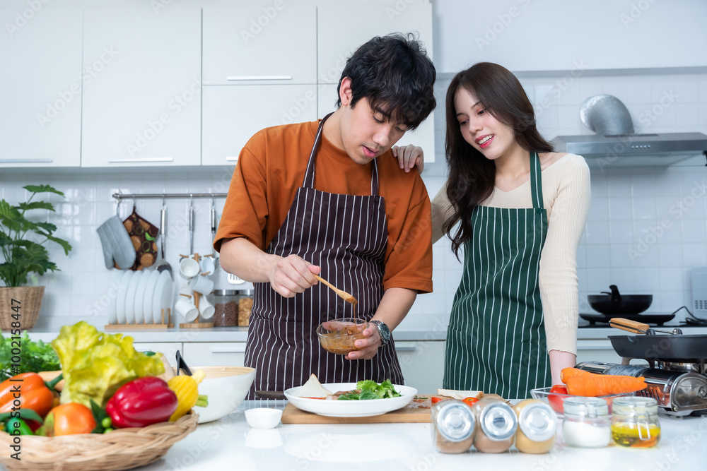 Happy portrait of loving young loving couple asian of having fun standing a cheerful preparing food and enjoy cook cooking with vegetables, meat, bread while standing on a kitchen Condo life or home