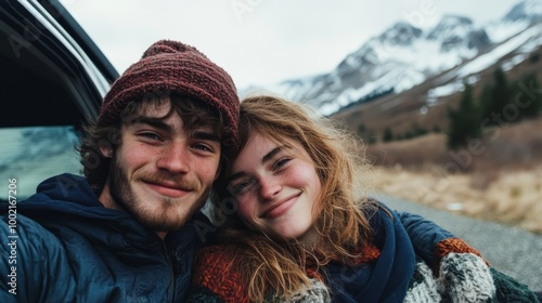 A joyful couple smiles for a selfie against a stunning mountain backdrop, showcasing their love and connection during an outdoor adventure.