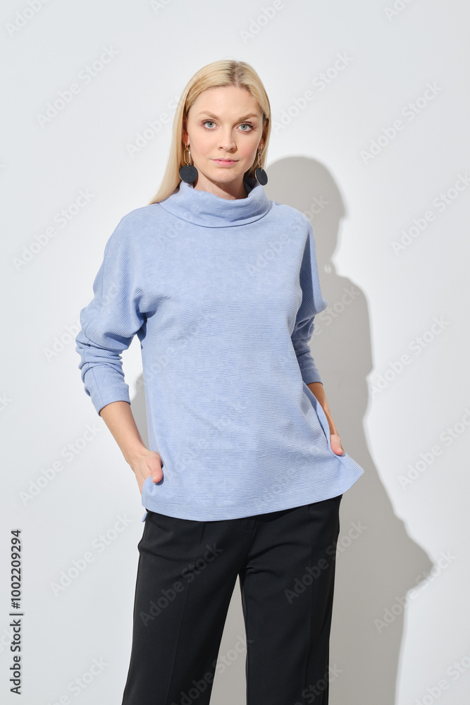 Studio portrait of classy woman in blue sweater and black trousers Studio portrait of classy woman in blue sweater and black trousers