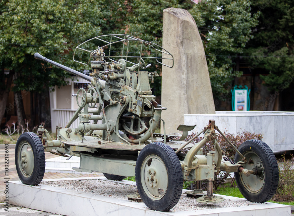 A large, old-fashioned military vehicle is on display in a park A large, old-fashioned military vehicle is on display in a park