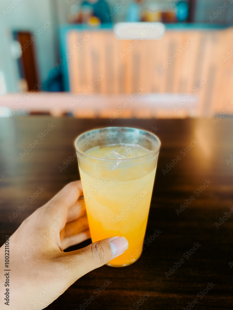 Hand holding a glass of iced orange juice Hand holding a glass of iced orange juice