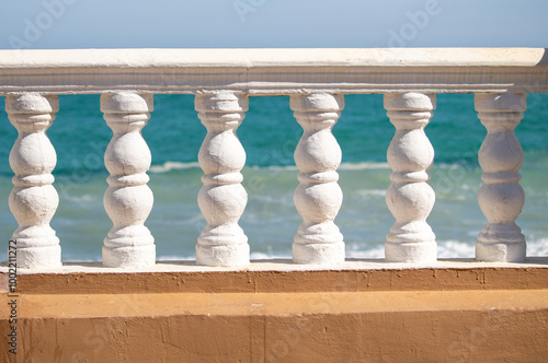 A white railing sits on a beach, overlooking the ocean