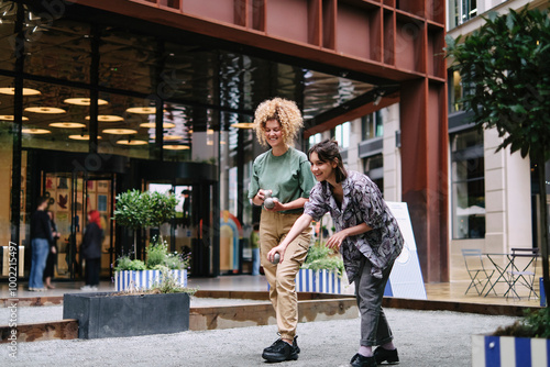 Happy lesbian couple playing boccia balls in fornt of building photo