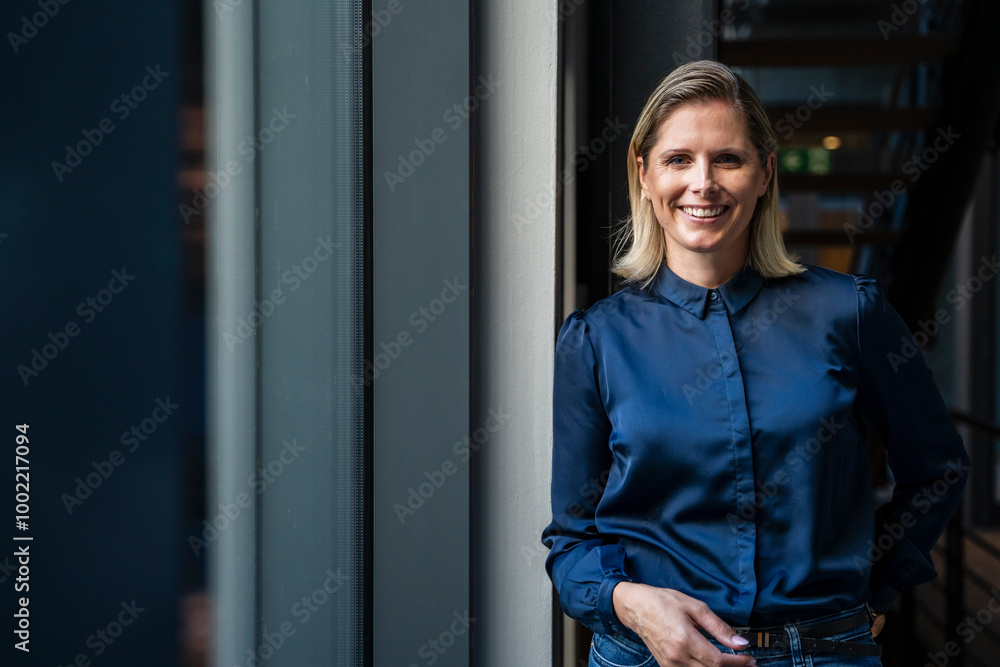 Happy blond businesswoman standing in corridor Happy blond businesswoman standing in corridor