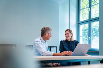 Happy businesswoman discussing with businessman at desk
