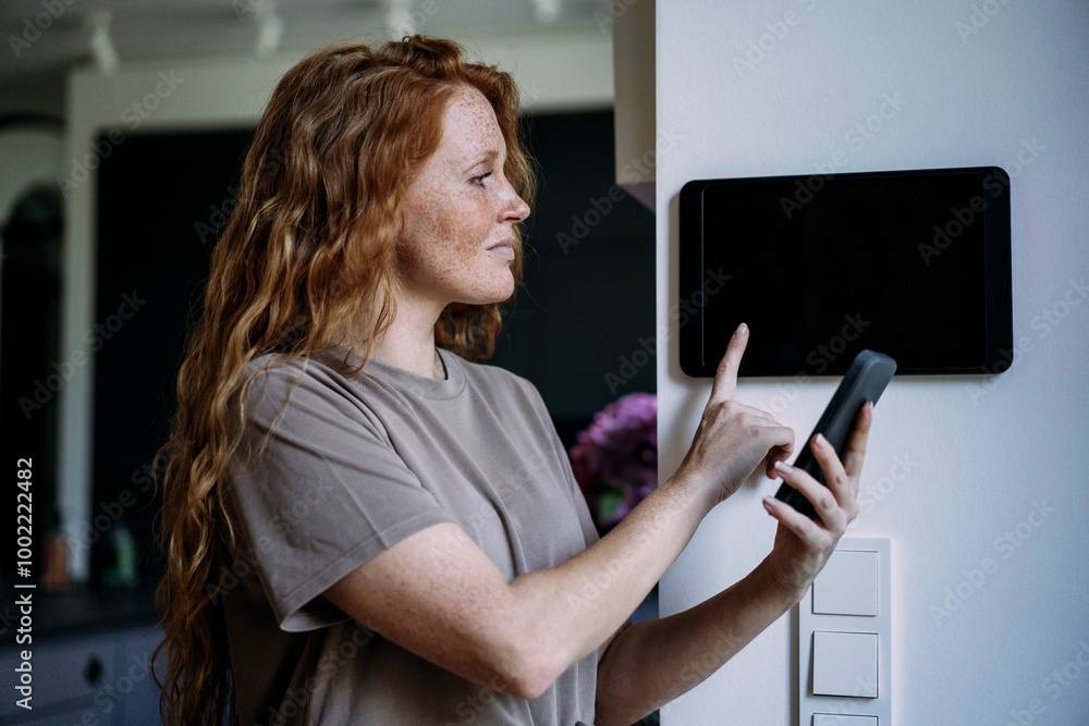 Redhead woman connecting smart phone with tablet PC at home Redhead woman connecting smart phone with tablet PC at home
