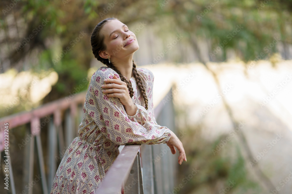 Smiling woman standing with eyes closed on bridge