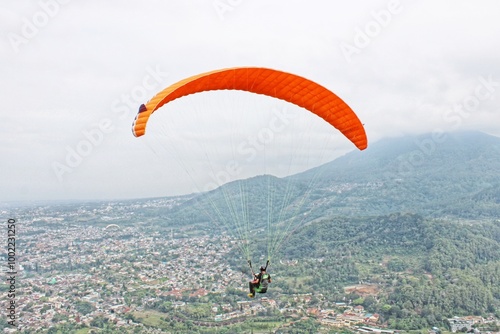 Paraglider flies high against the background of blue sky and mountain view photo