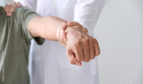 Female doctor hand rehab physical therapy by extending the pain shoulder of a patient. treatment with stretch exercises