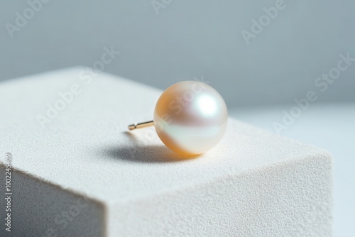 A single pearl earring rests elegantly on a textured surface, showcasing its lustrous sheen and minimalist design. photo