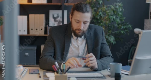 Businessman making money transaction with credit card and computer sitting at desk focused on business development and finance. photo