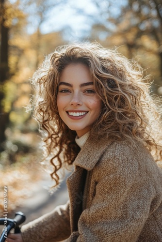 Young woman with curly hair smiles on a bicycle during autumn in the park