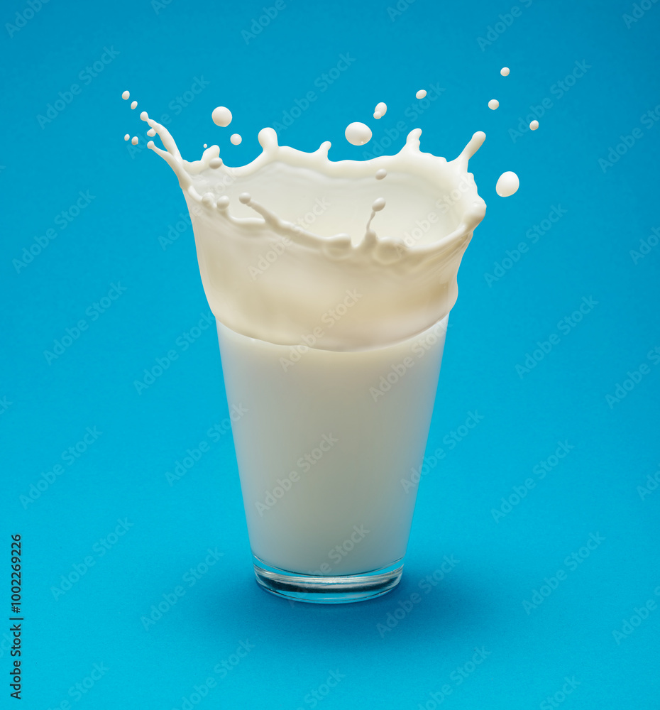 Milk splash (crown) on a glass of milk isolated on blue background. Milk splash (crown) on a glass of milk isolated on blue background.