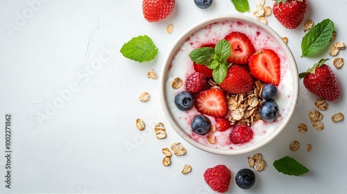 Fresh berry yogurt bowl with oats and mint on a white background