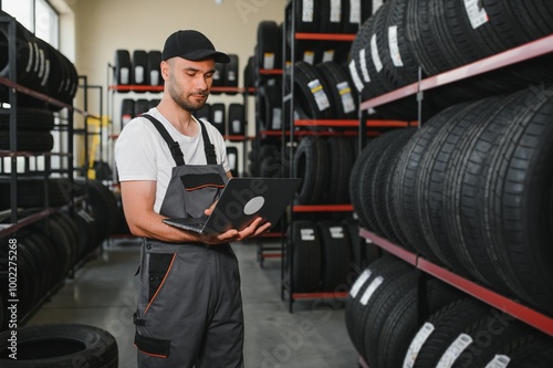 mechanic in blue uniform standing at stock tyre