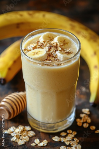 Creamy banana smoothie topped with oats and honey on a wooden table