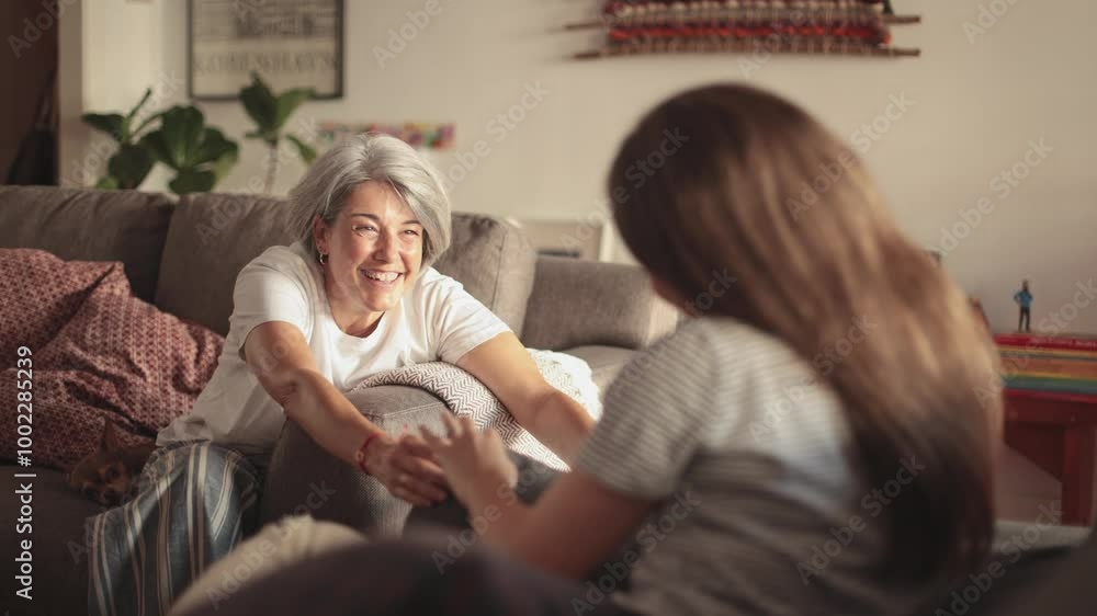 Mother and daughter enjoying a chat on sofa at home Mother and daughter enjoying a chat on sofa at home