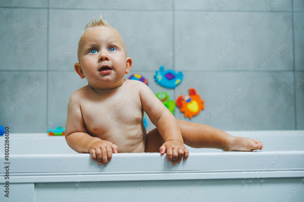 Blond toddler standing in white bathroom and smiling. The child bathes independently. Blond toddler standing in white bathroom and smiling. The child bathes independently.