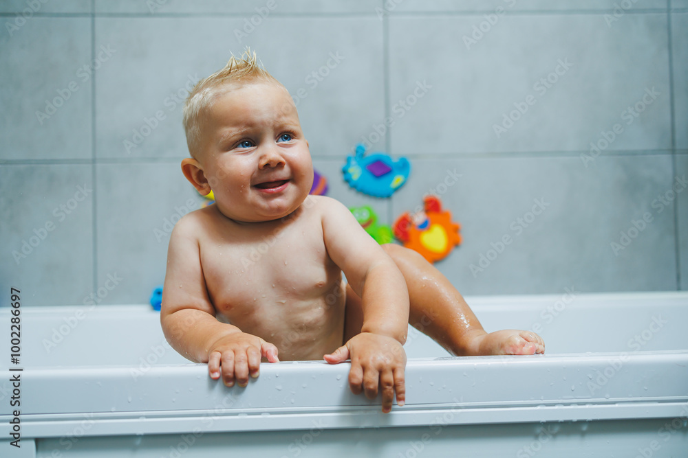 Blond toddler standing in white bathroom and smiling. The child bathes independently. Blond toddler standing in white bathroom and smiling. The child bathes independently.