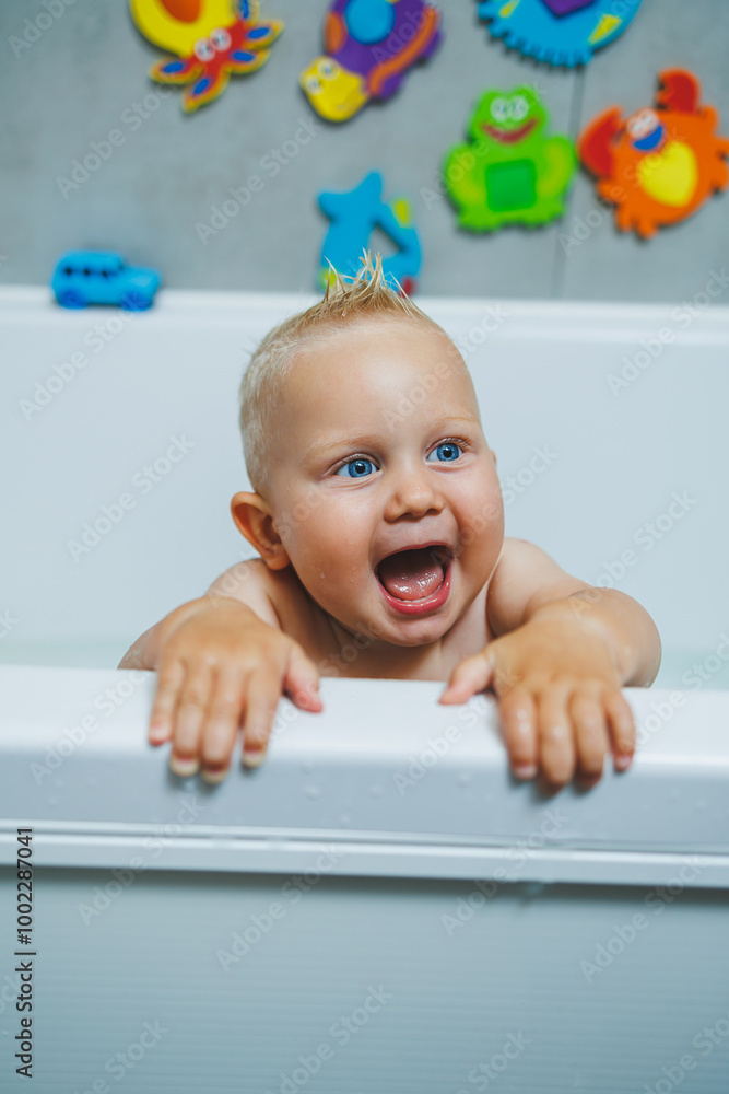 Blond toddler standing in white bathroom and smiling. The child bathes independently. Blond toddler standing in white bathroom and smiling. The child bathes independently.