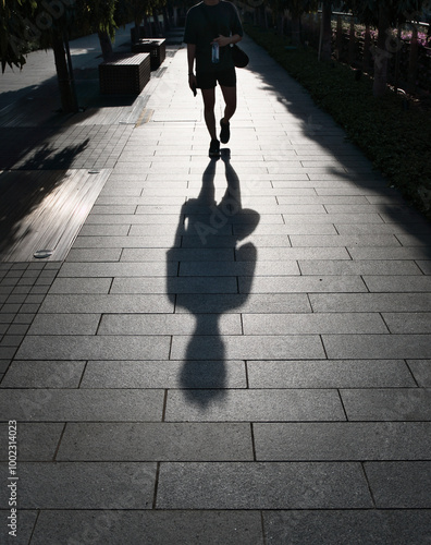 Shadow of man walking on walkway in city