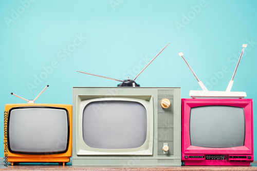 Retro TVs set on table front mint blue background. Vintage old style filtered photo