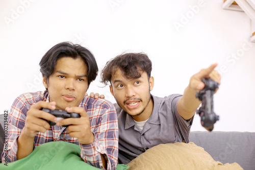 Two Asian Guys Playing Video Games on The Console Game While Sitting on The Couch.