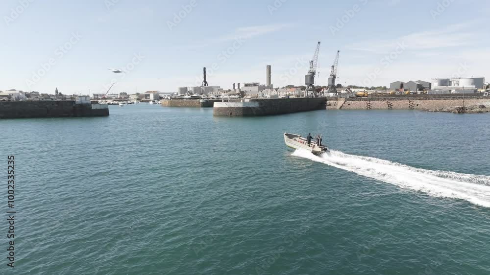 Guernsey, open boat speeding to entrance of St Sampsons Harbour on bright sunny day showing docks,cranes and harbour entrance Guernsey, open boat speeding to entrance of St Sampsons Harbour on bright sunny day showing docks,cranes and harbour entrance