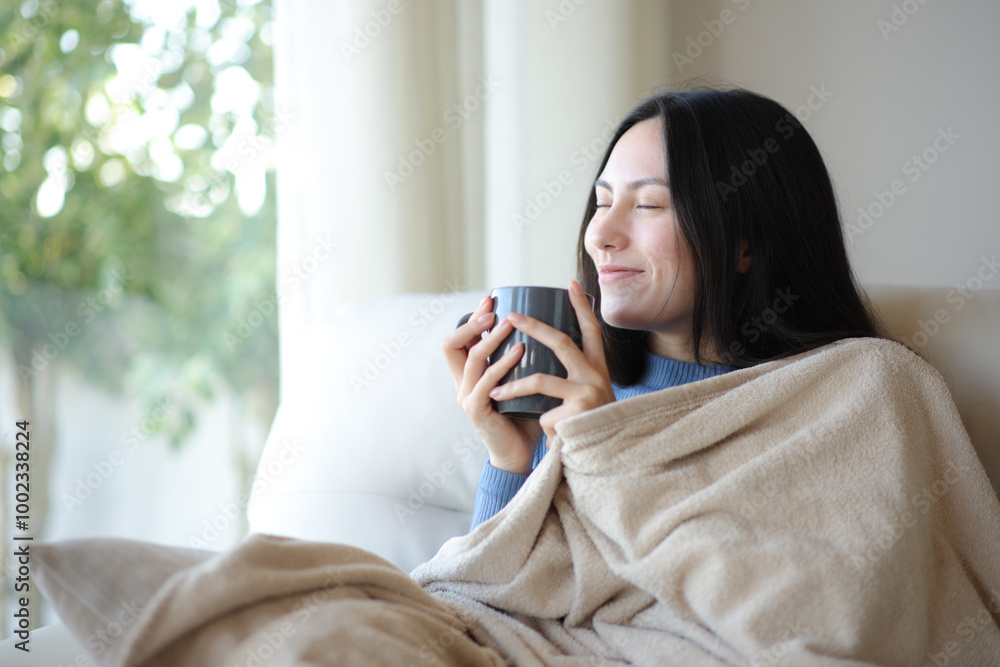 Asian woman in winter drinking coffee covered with blanket at home Asian woman in winter drinking coffee covered with blanket at home
