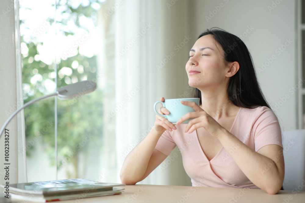Asian woman smelling coffee and breathing at home Asian woman smelling coffee and breathing at home