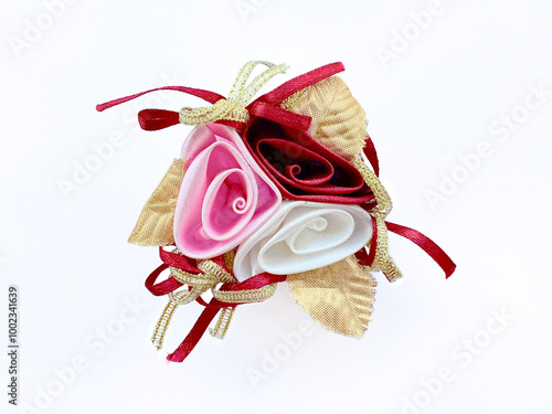 Flower corsage brooch arrangement in colors of pink, red, and white rose with gold leaves and ribbons. Cheerful red flower corsage accessories or decoration for clothes. Isolated on white background. photo