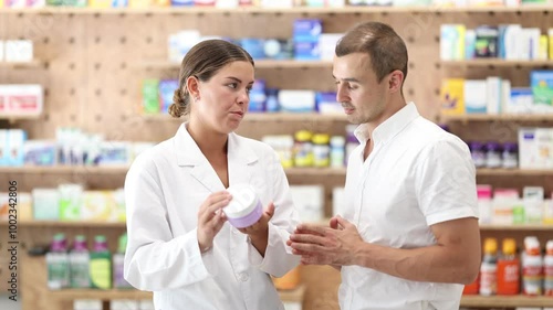 Wallpaper Mural Female consultant pharmacist holds cream in hands and offers man client to purchase remedy to alleviate condition. Specialist recommendations according to clients problem, help at pharmacy.  Torontodigital.ca