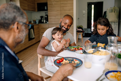 Happy multigenerational family having breakfast on dining table at home photo