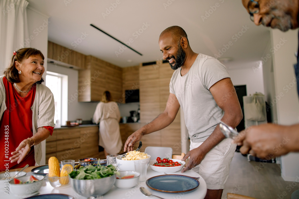 Happy family members helping each other in setting dining table for lunch at home Happy family members helping each other in setting dining table for lunch at home