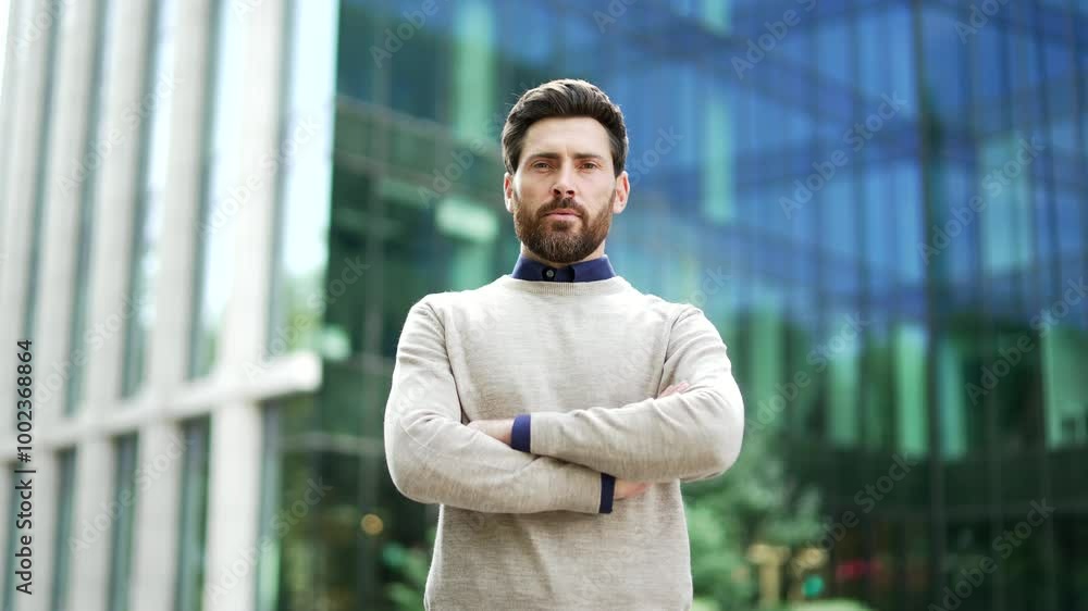 Portrait of confident serious male professional standing outdoors on the street near business office building with arms crossed. Man worker exudes professionalism and authority looking into the camera Portrait of confident serious male professional standing outdoors on the street near business office building with arms crossed. Man worker exudes professionalism and authority looking into the camera