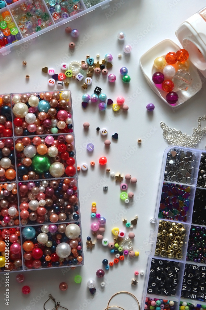 Colorful beads, letter beads, threads and other jewelry making supplies on white background. Making friendship bracelets concept. Flat lay.