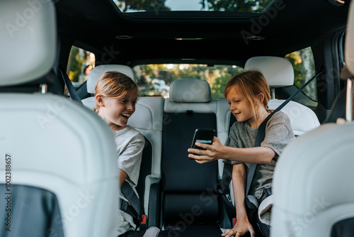 Boy showing smart phone to brother sitting in car during road trip photo