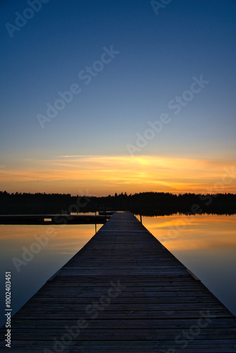 Wooden jetty at sunset on a Swedish lake. Sunset reflected in the water