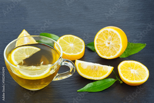 Cup of tea and some pieces of lemon on a black background photo