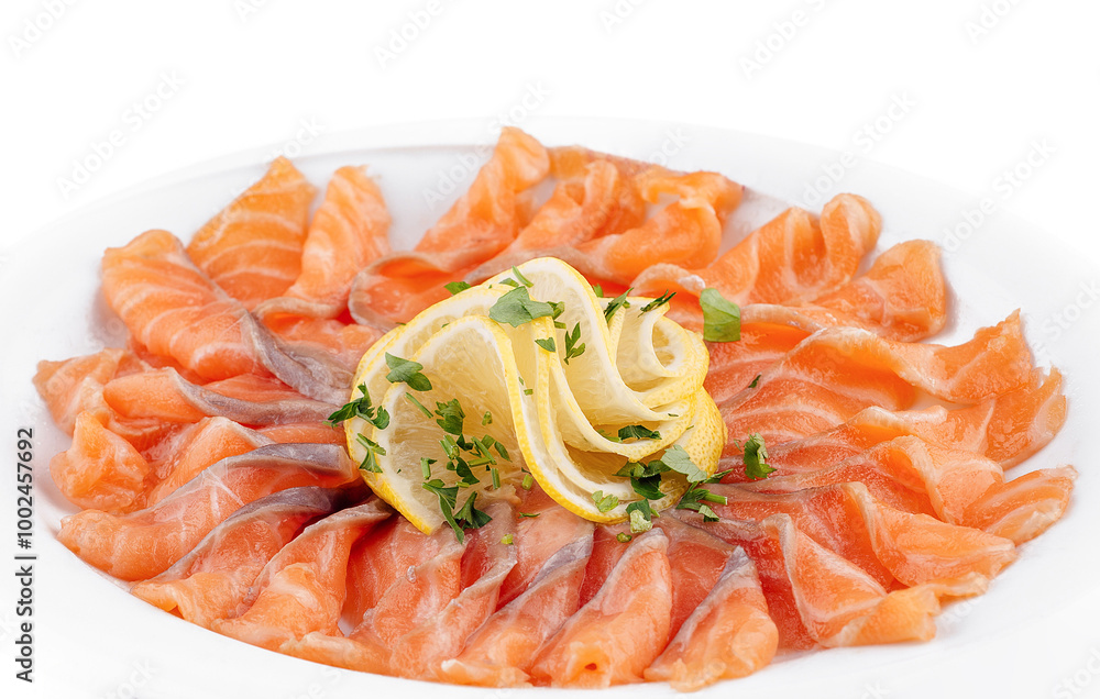 Sliced salmon fillet decorated with lemon and parsley on white plate Sliced salmon fillet decorated with lemon and parsley on white plate