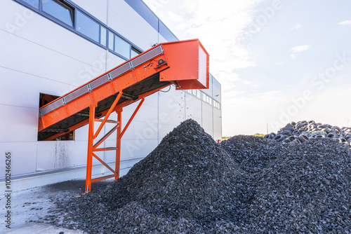 Tire recycling facility with shredded rubber piles and conveyor belt