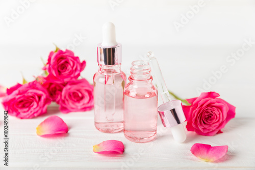 Rose essential oil on a textured background.Roses and a bottle of rose perfumed water.Aromatherapy treatment. Beauty concept. Spa procedure.Natural organic oil.Anti-stress,detox relax.Place for text